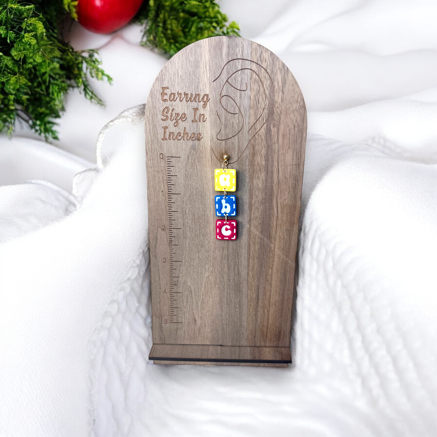 Stacked ABC block earrings displayed on a wooden earring size chart, showing their playful design and length.
