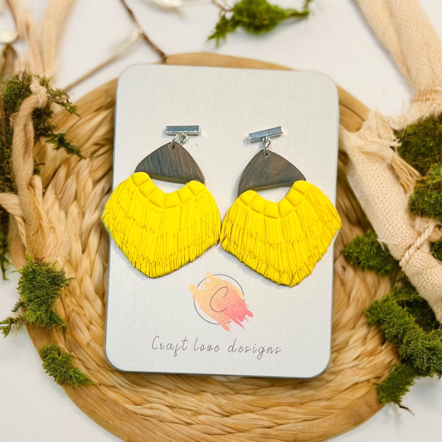 Handmade polymer clay earrings featuring a bright yellow fan design and wooden tops, showcased on a Craft Love Designs branded card.