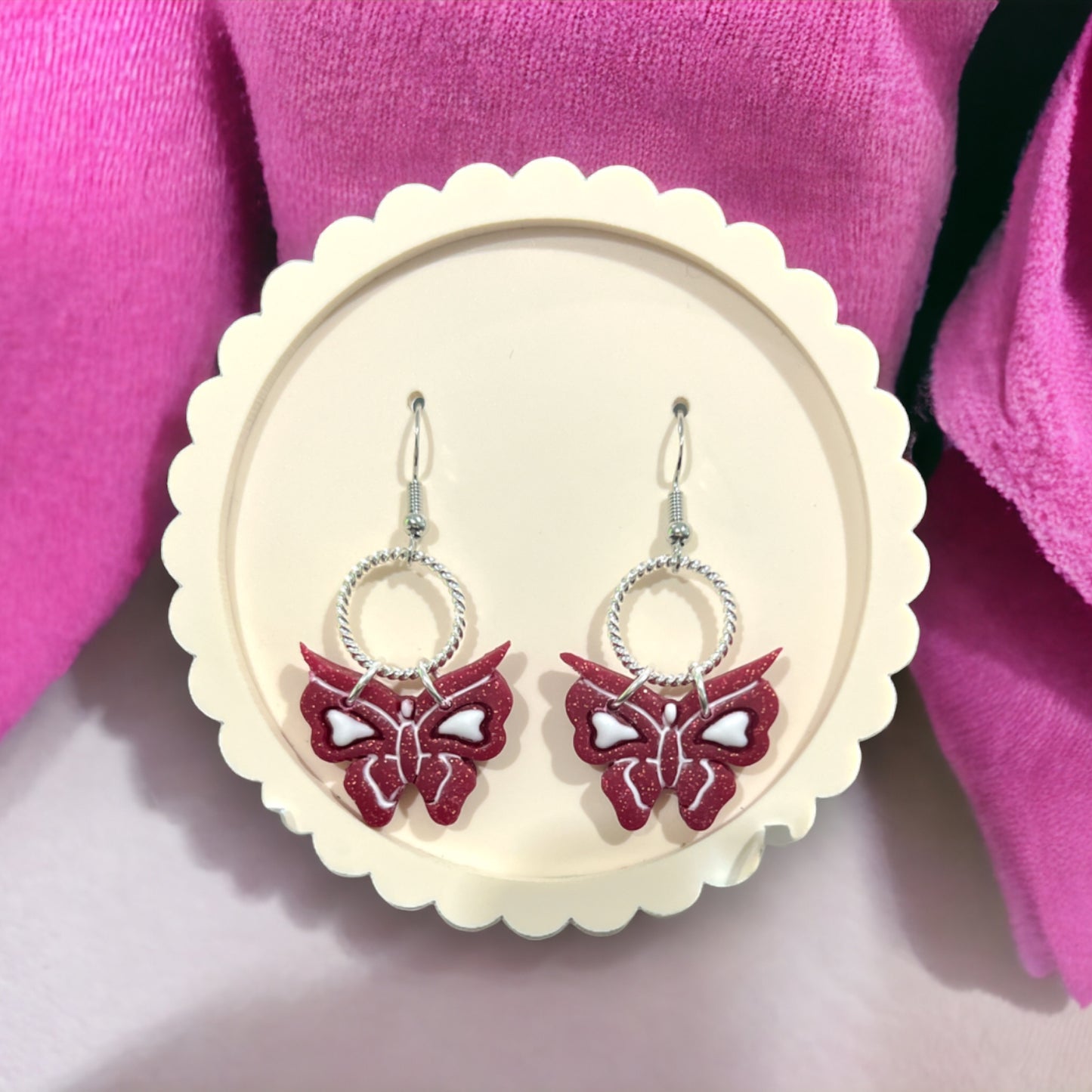 Unique dangle earrings with pink glitter butterflies, white hearts, and silver accents, designed for whimsical and chic styling.