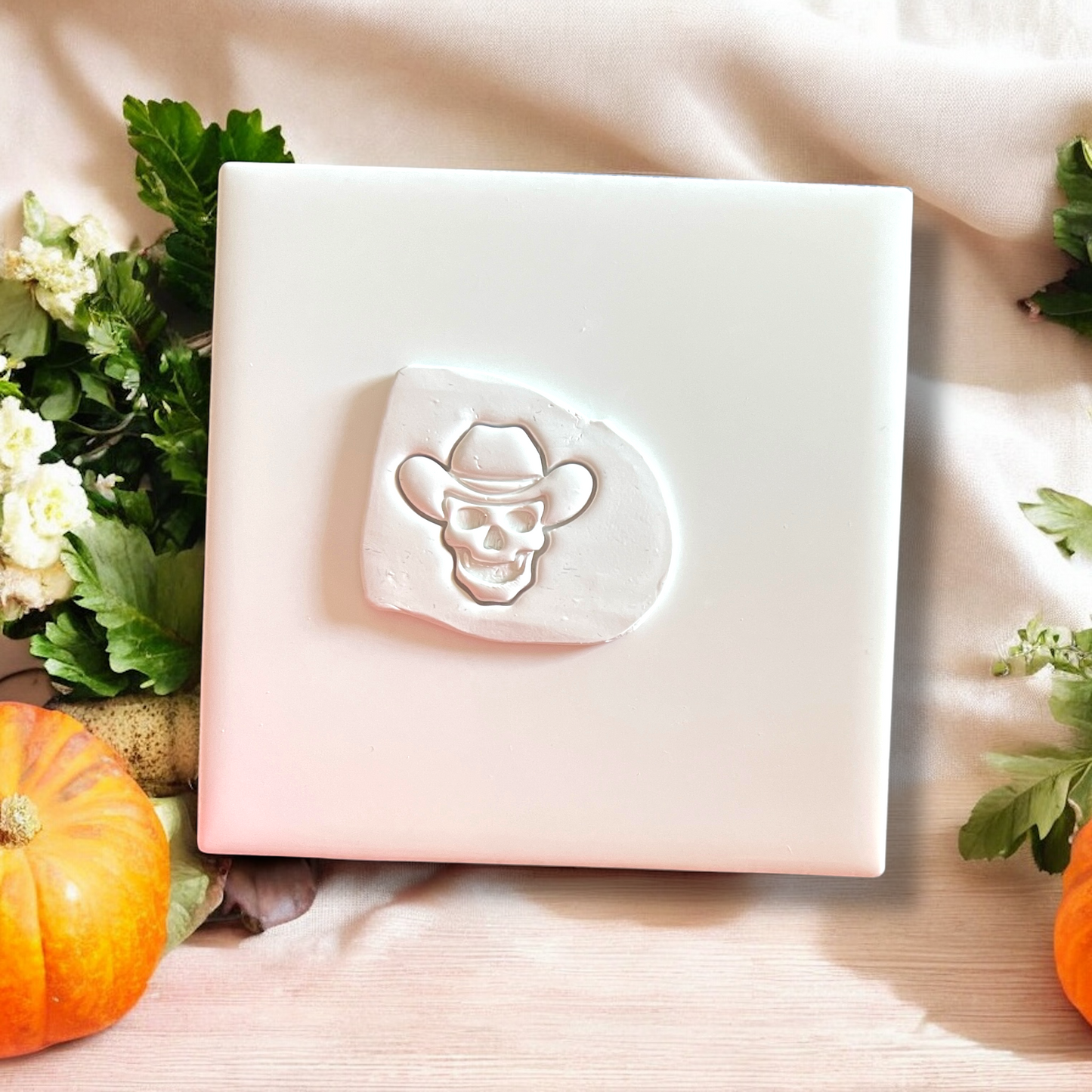 Cowboy skull clay impression on white tile with pumpkins and leaves