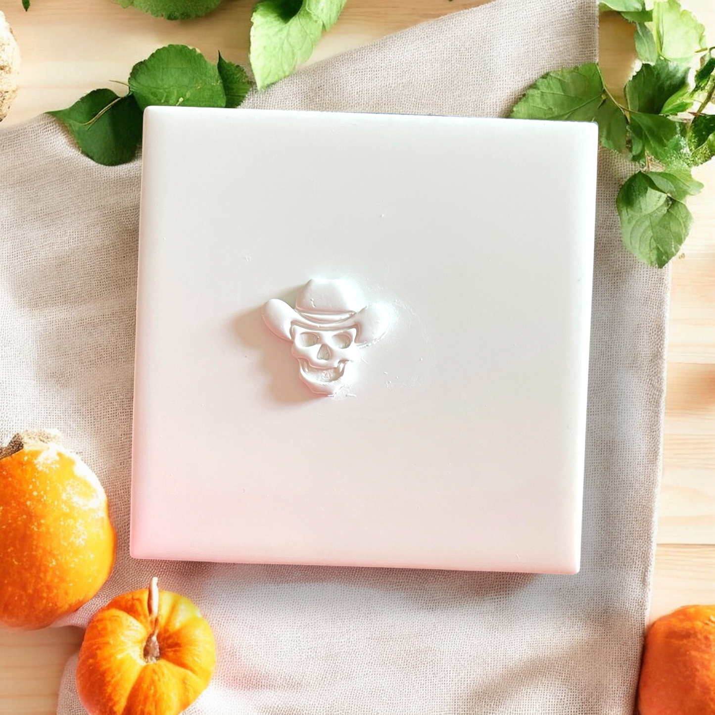 Deep embossed cowboy skull on white tile with linen background