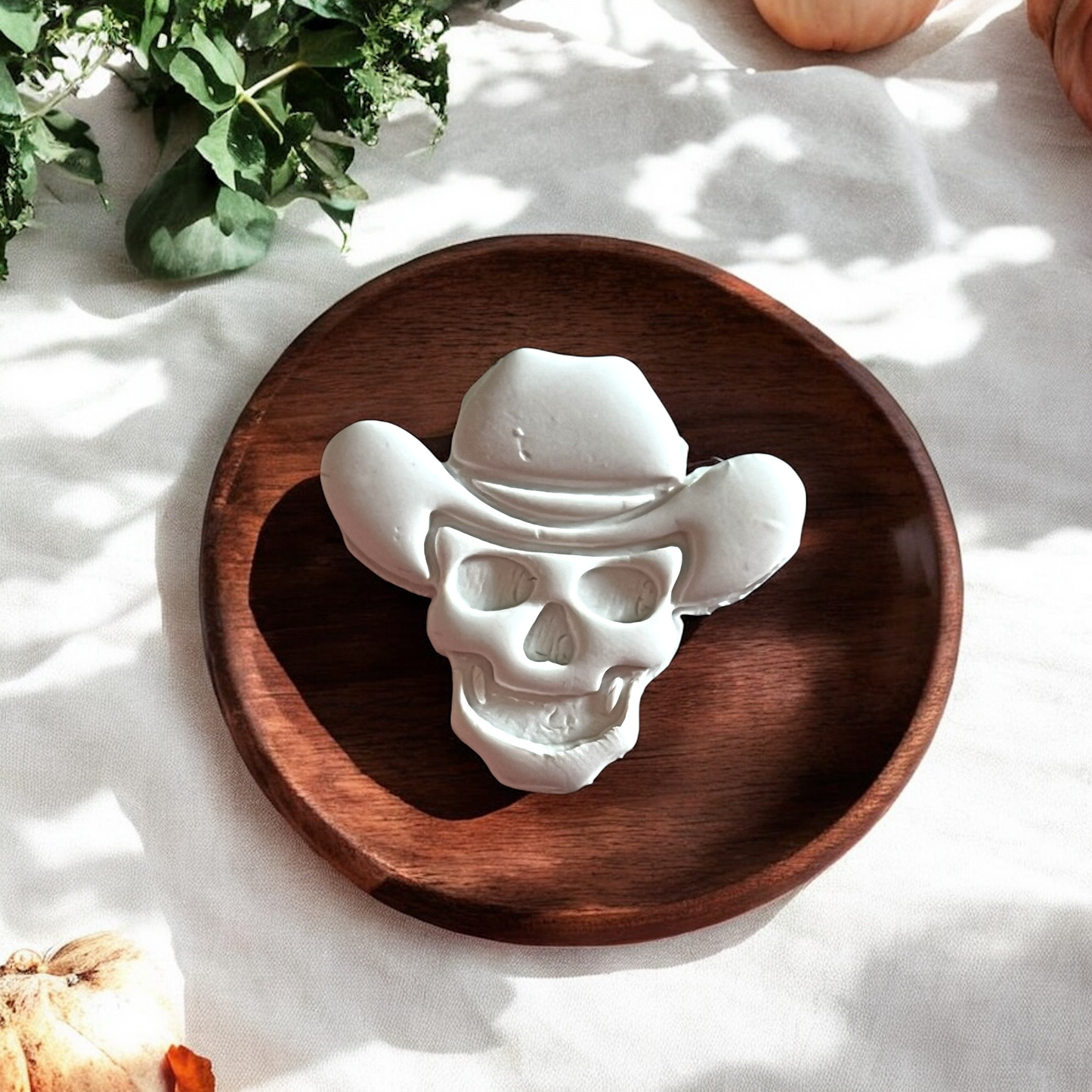 Close-up of large cowboy skull clay piece on wooden plate with soft shadows