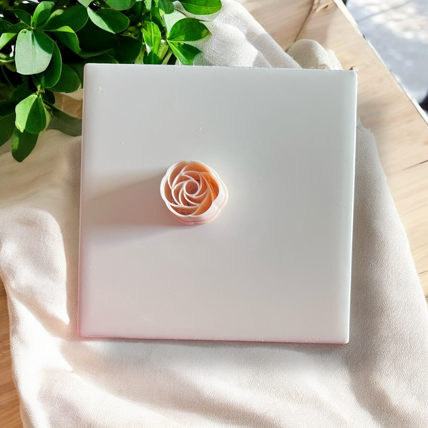 peach-toned polymer clay rose topper with soft shadows and greenery