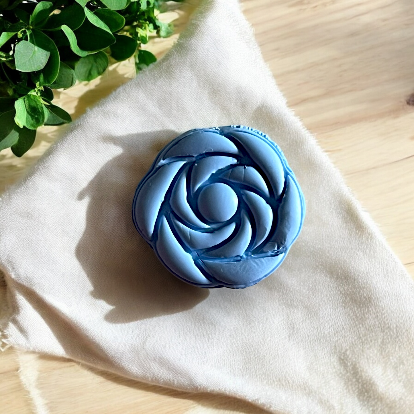 close-up of sculpted blue rose impression in polymer clay on fabric