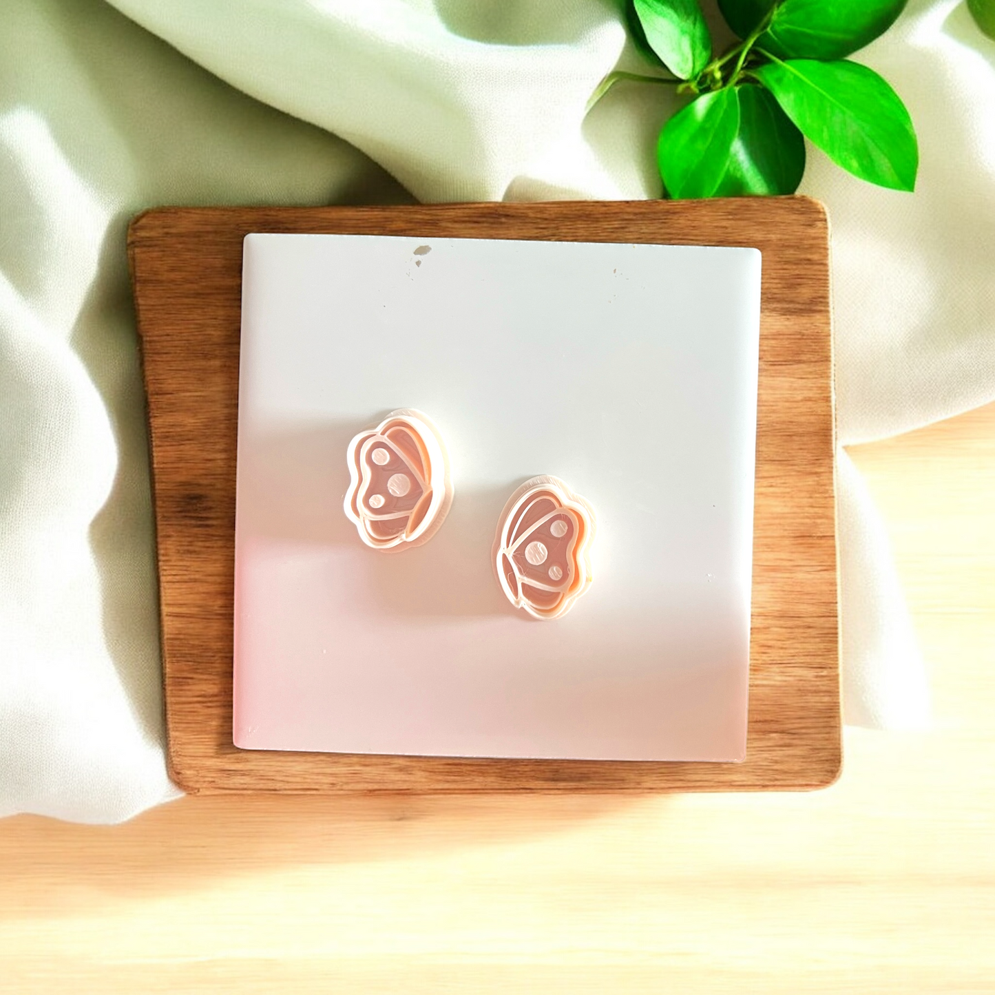 Butterfly-shaped earrings on a wooden stand with a soft background