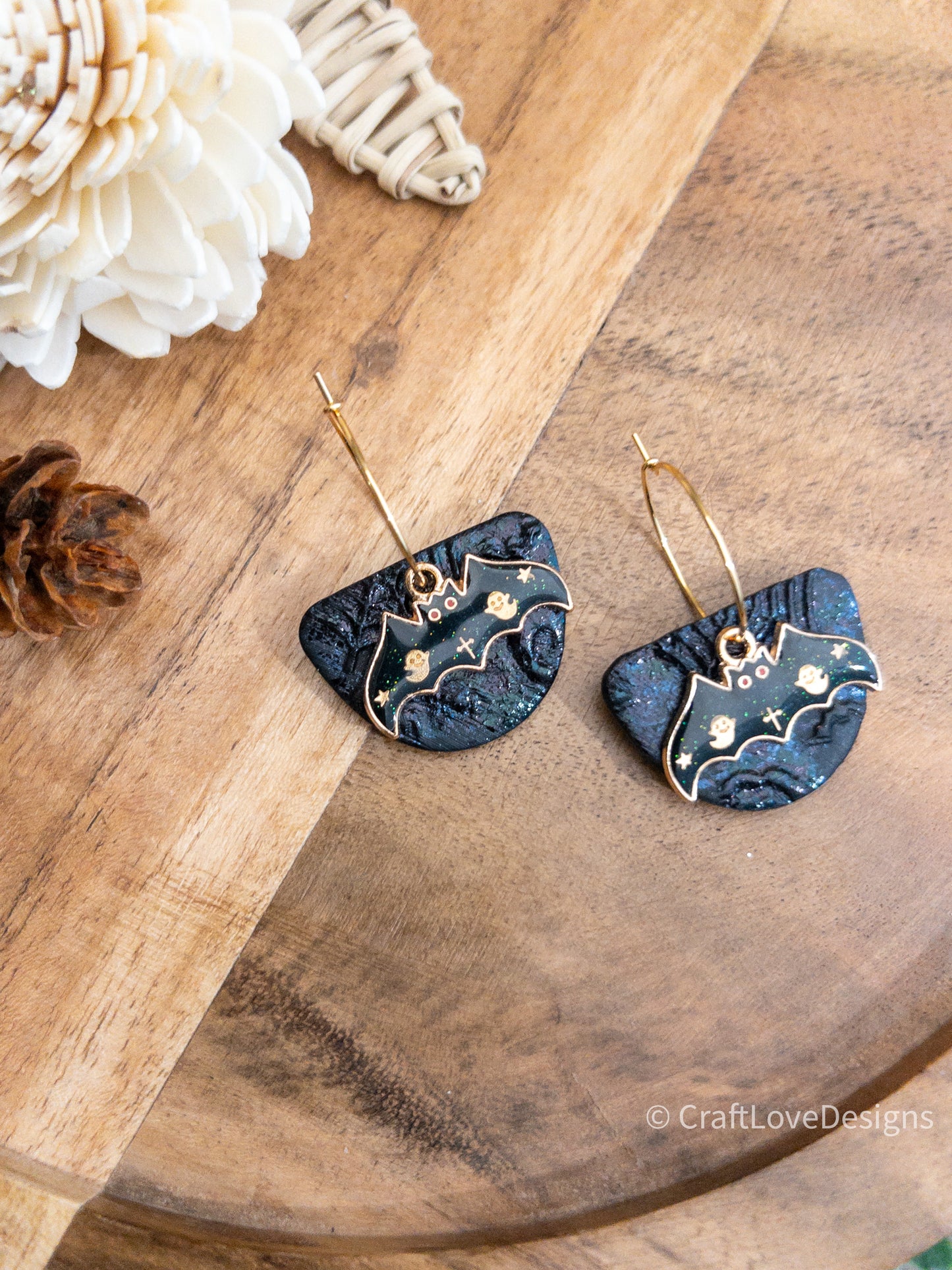 Stylish black and gold Halloween bat earrings, highlighted with glitter texture and ghostly gold bat charms, ideal for spooky occasions.