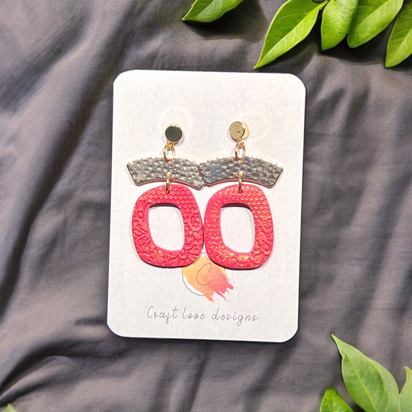 Handcrafted red dangle earrings with gold-tone accents, showcasing textured organic patterns and a lightweight artisanal charm.