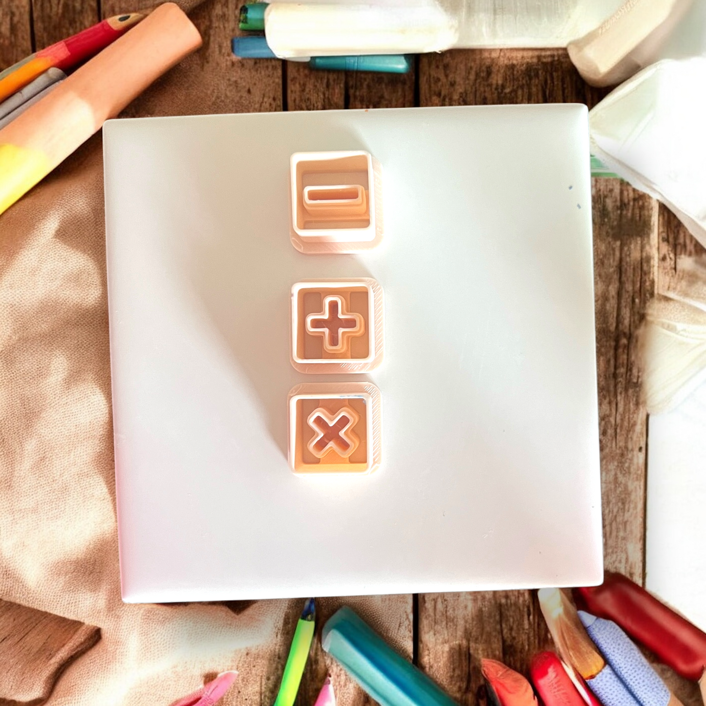 Top-down photo of subtraction, addition, and multiplication cutters in peach color neatly arranged in a column.