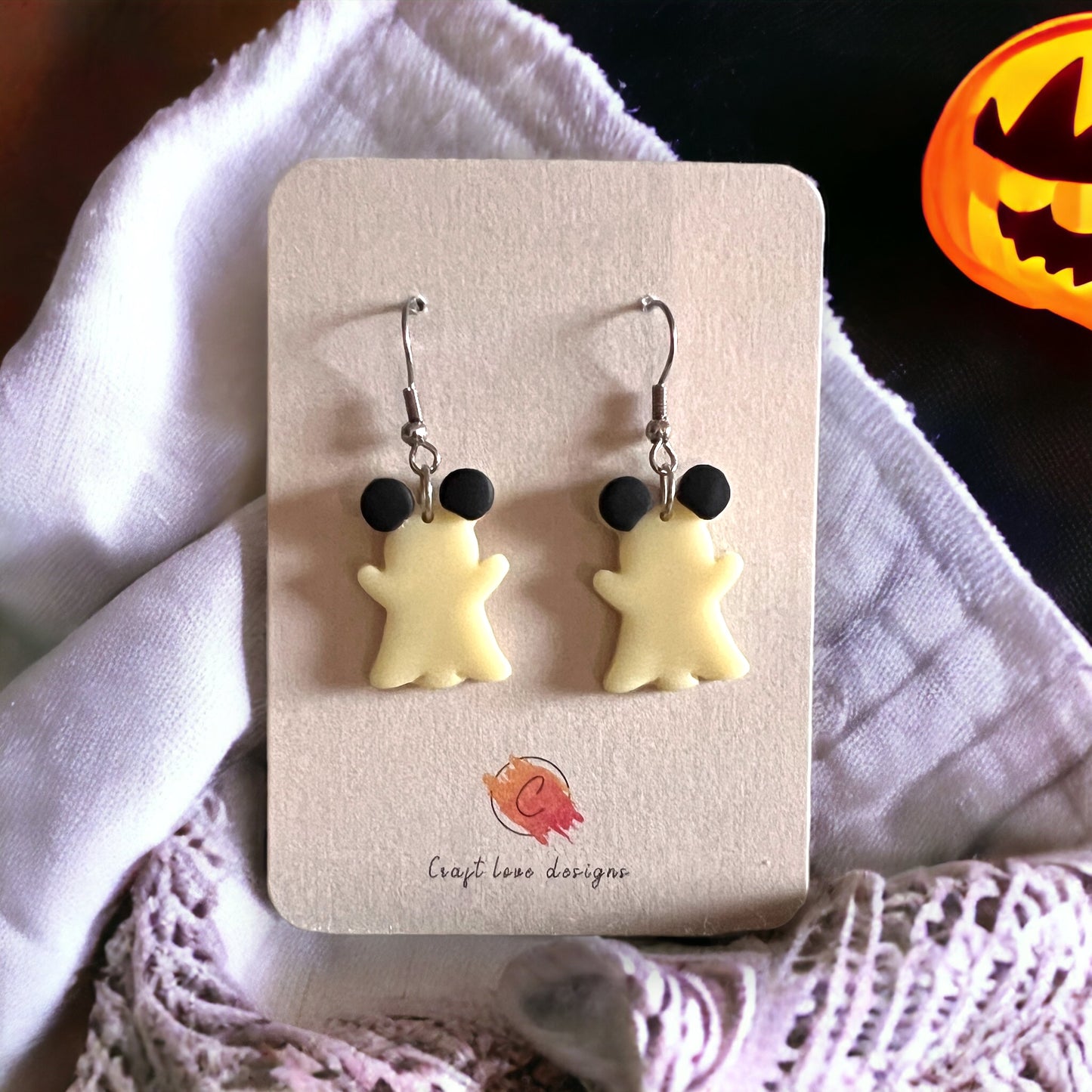 Mouse ghost dangle earrings glowing against a Halloween-themed background, highlighting their cute black ears and spooky playful vibe.