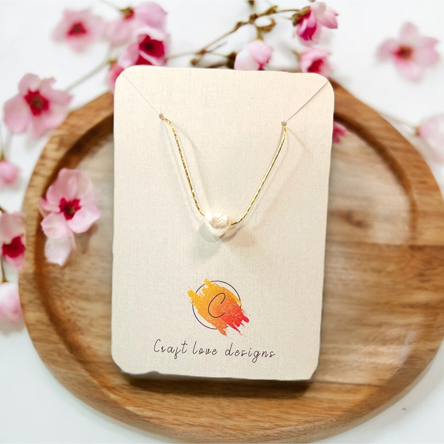 Close-up of a natural pearl necklace elegantly positioned on a display card with floral surroundings, highlighting its minimalistic beauty.