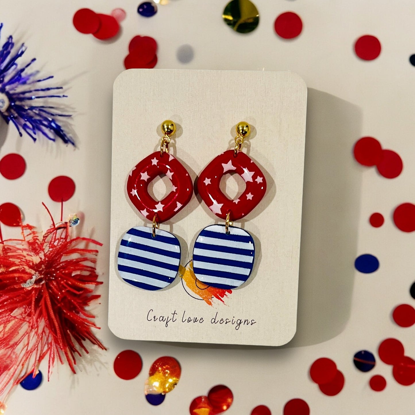 Festive red and blue polymer clay dangle earrings with bold star and stripe patterns, perfect for patriotic celebrations.