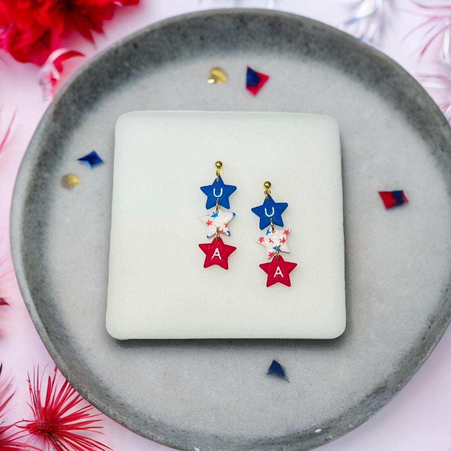 Red, white, and blue polymer clay USA star dangle earrings with gold accents, perfect for 4th of July celebrations and events.