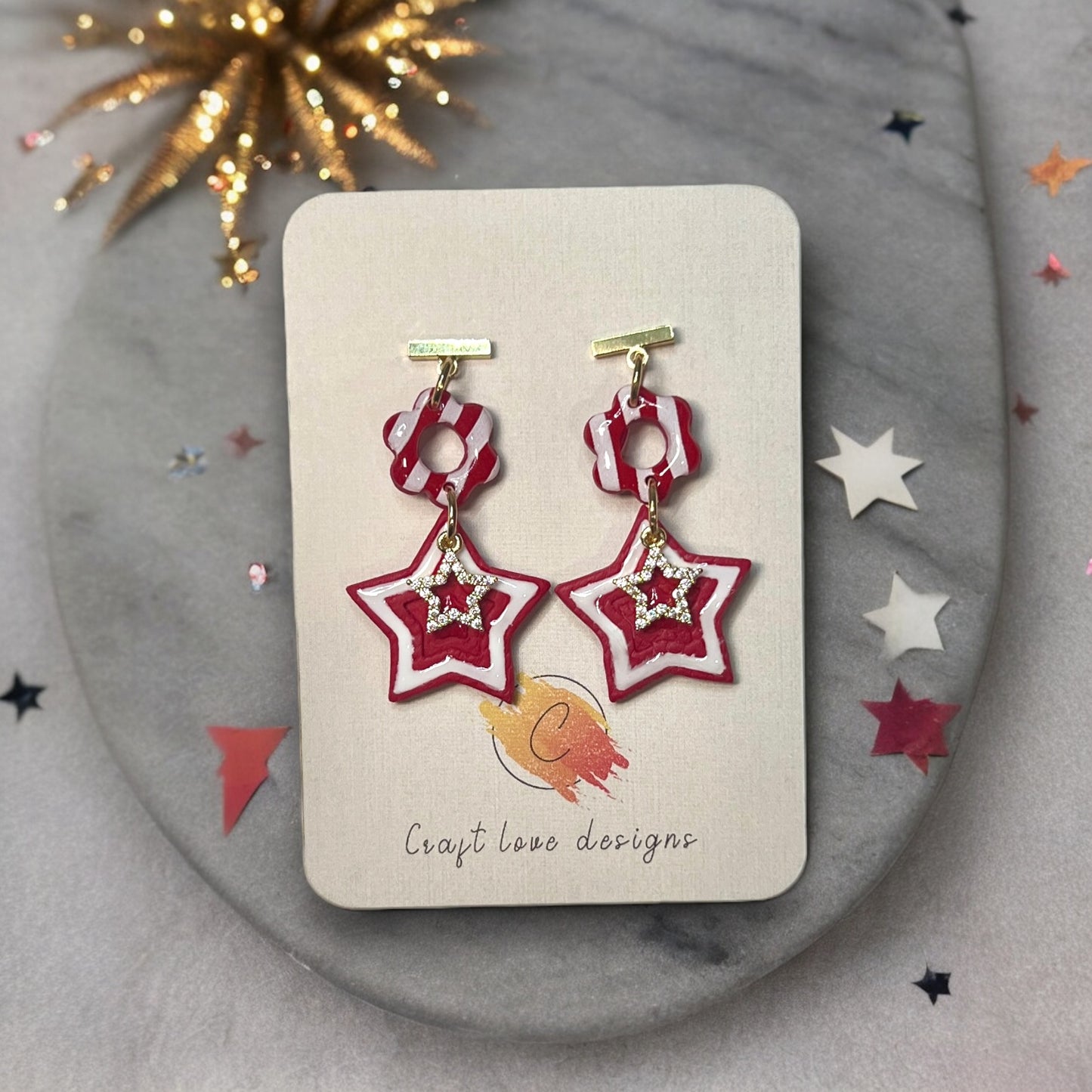 Red festive 4th of July polymer clay dangle earrings with bold, vibrant details, perfect for patriotic holiday celebrations on an earring card.