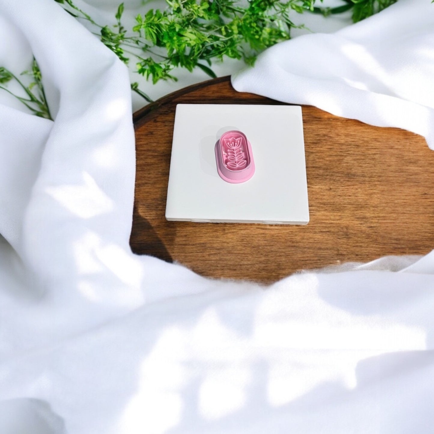 Pink embossed clay cutter resting on white ceramic tile with natural lighting