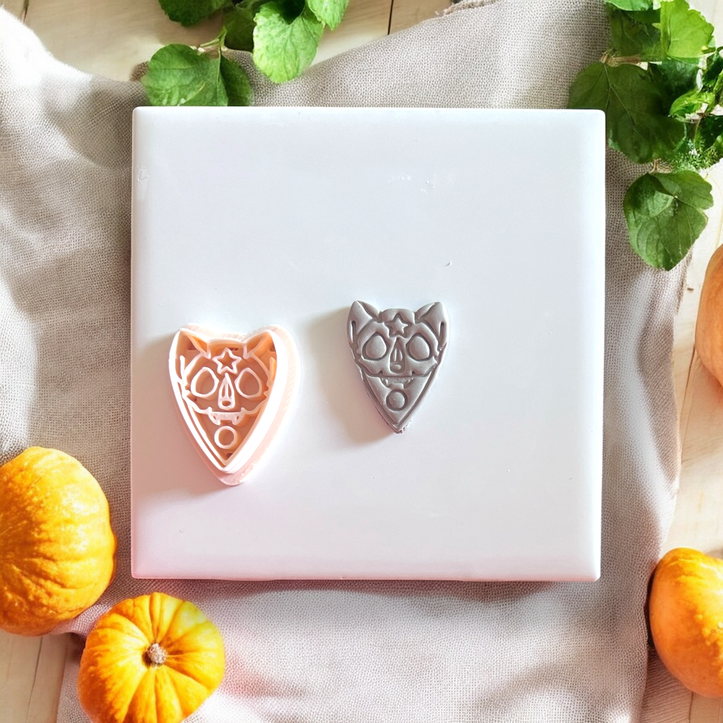 Side-by-side of clay cutout and pink cutter of sugar skull cat shape