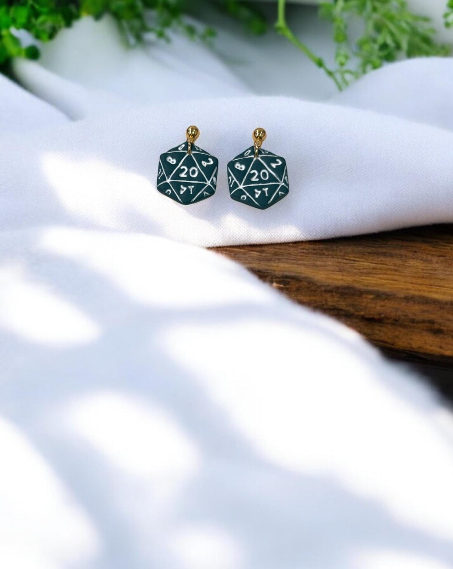 Final pair of polymer clay earrings featuring white numbered D20 design in deep green