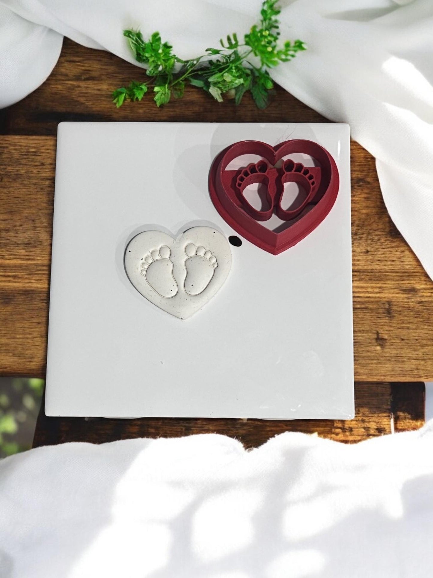 Red polymer clay cutter beside finished heart with feet imprint