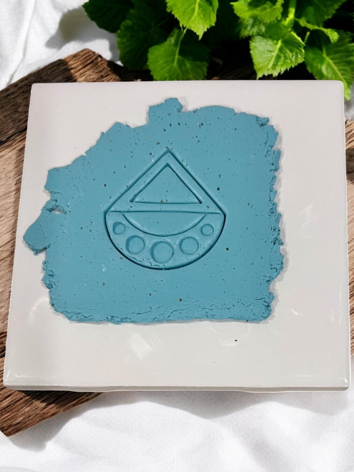 Blue polymer clay slab with geometric triangle and half-circle cutter impression