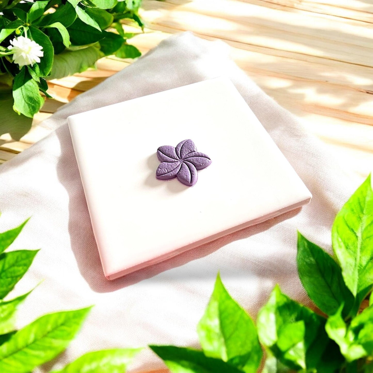 single plumeria clay flower on white tile