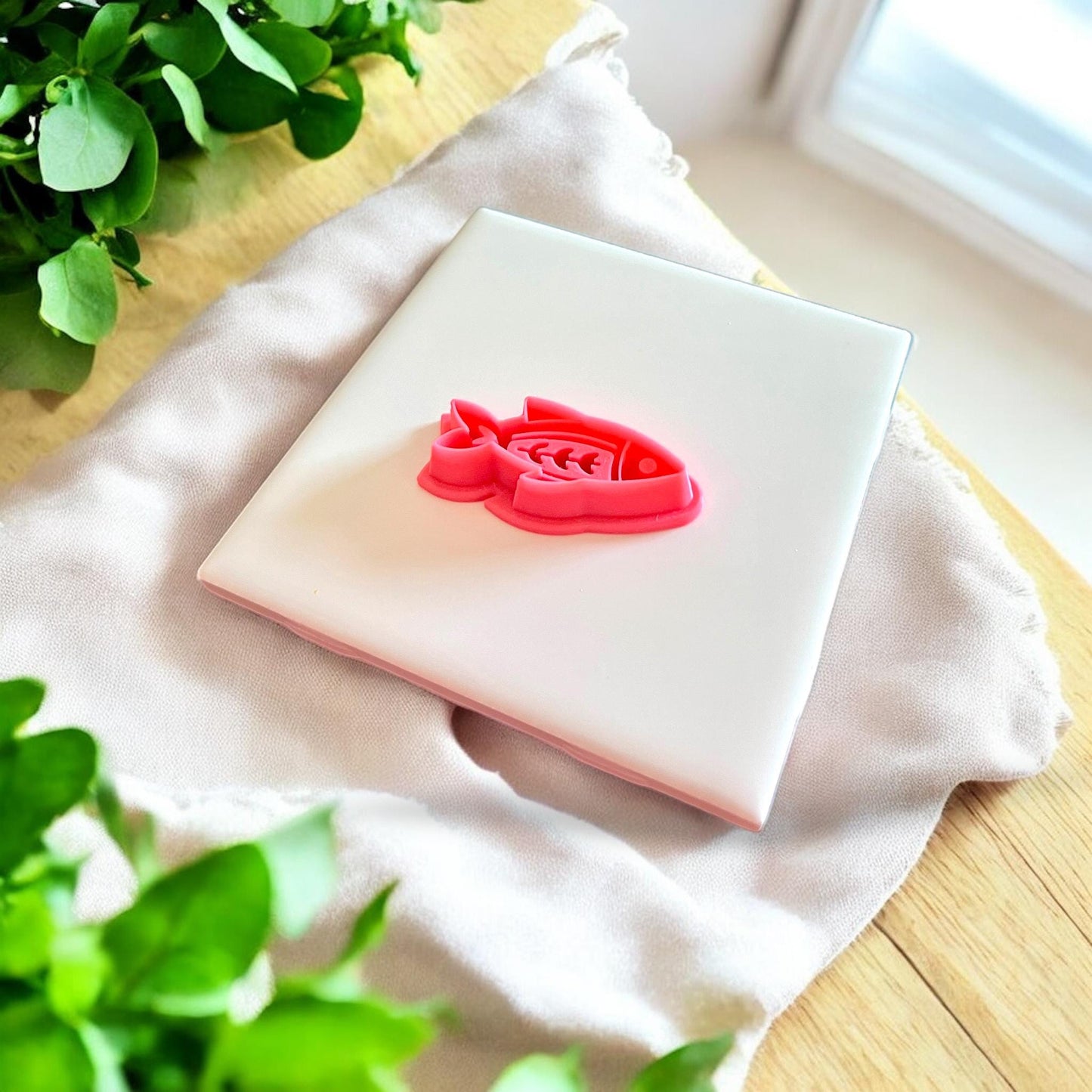 Red fishbone earring cutter shown on white tile