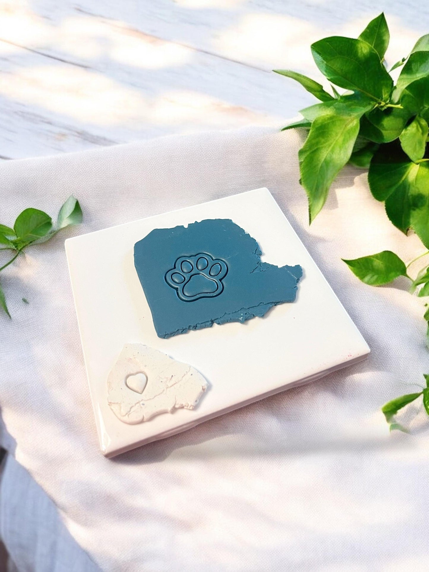Blue polymer clay slab with an imprint of a paw print design featuring a heart in the center, made using a pet-themed cutter