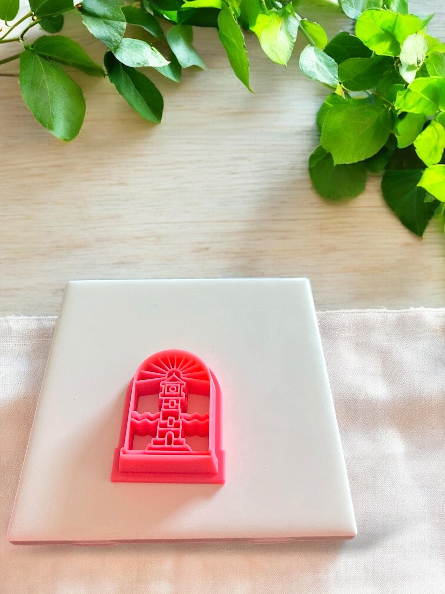 Pink 3D printed lighthouse polymer clay cutter in an arched frame design for creating scenic summer coastal jewelry pieces