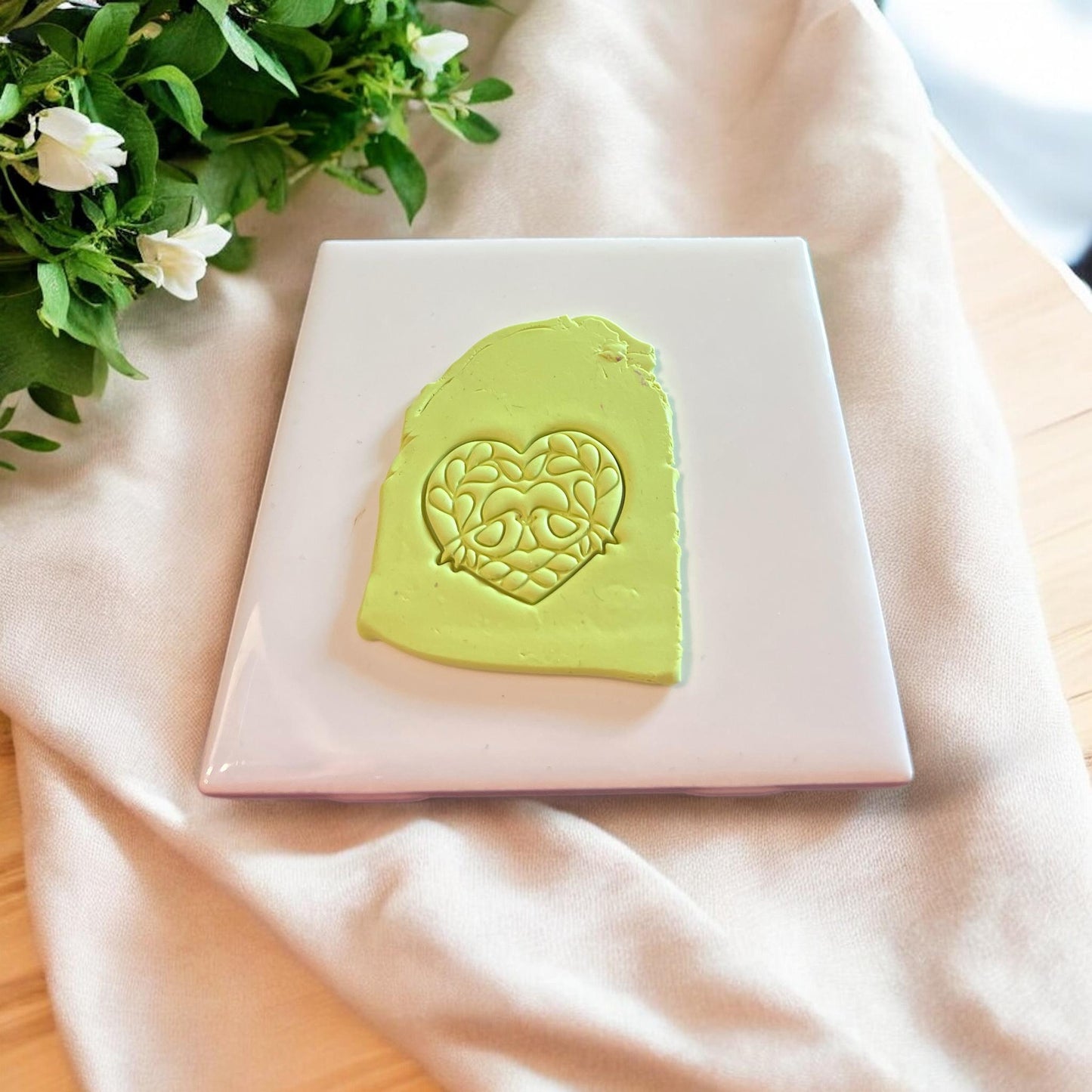 Lime green slab of polymer clay with detailed heart-shaped impression of love birds and florals.