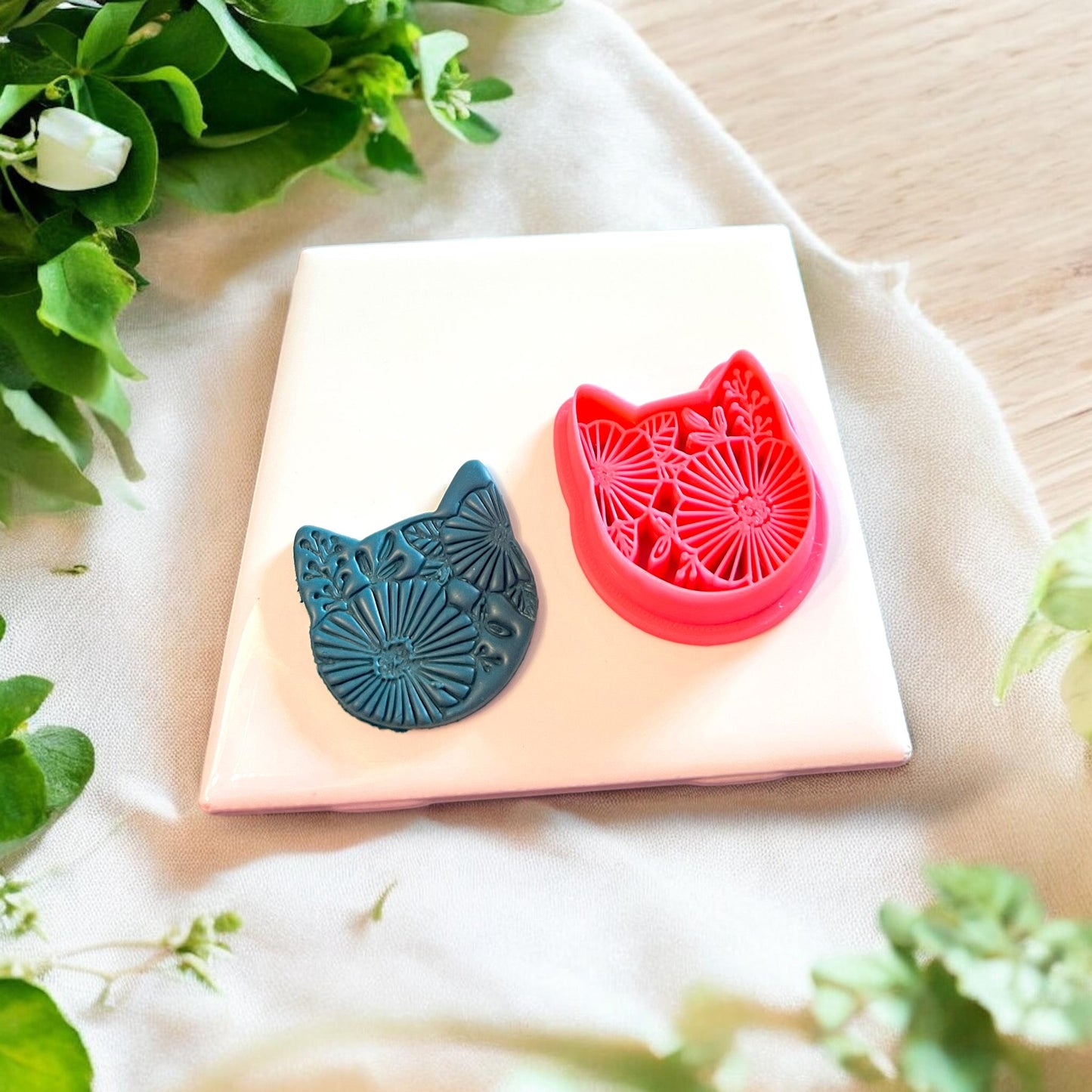 Polymer clay cutter shaped like a cat adorned with floral elements, perfect for earrings and charms.