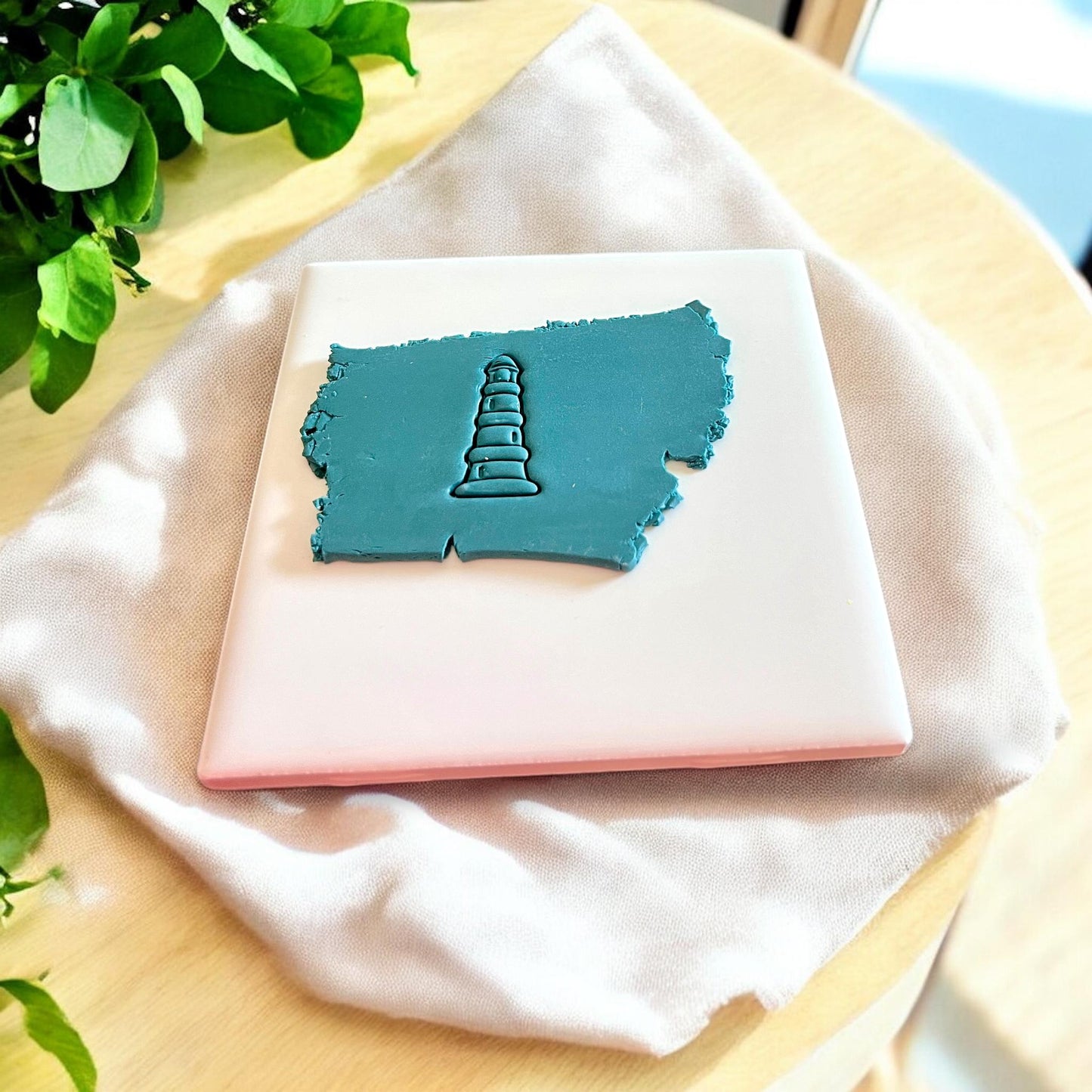 3D-printed lighthouse-shaped clay cutter placed on a slab of polymer clay, showcasing its design.