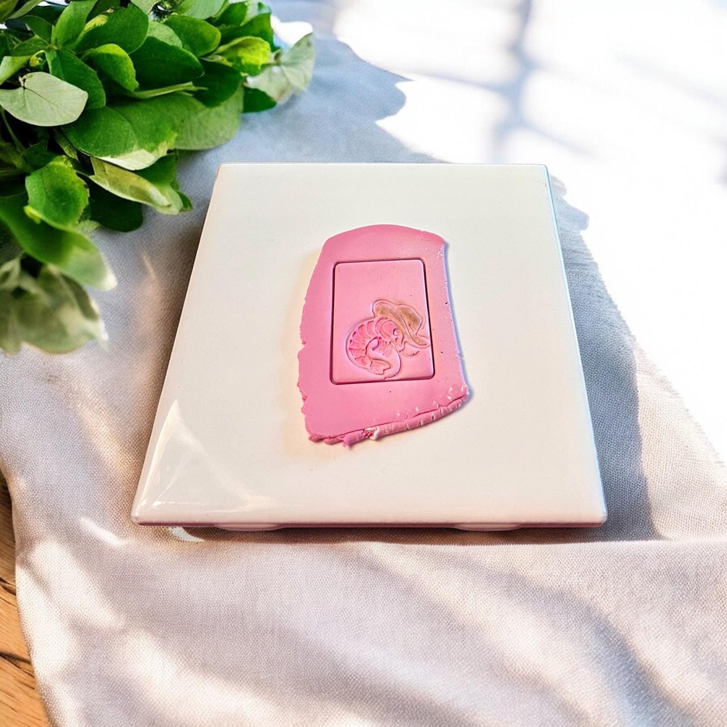 Polymer clay slab shows a funny lobster wearing a cowboy hat, cut using a rectangular arch earring mold.