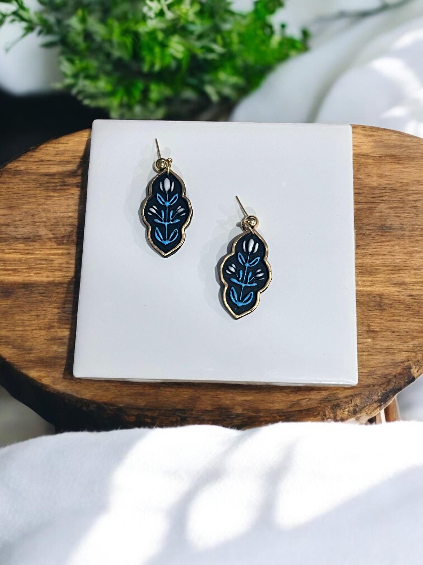Pair of black and blue polymer clay earrings with layered botanical pattern