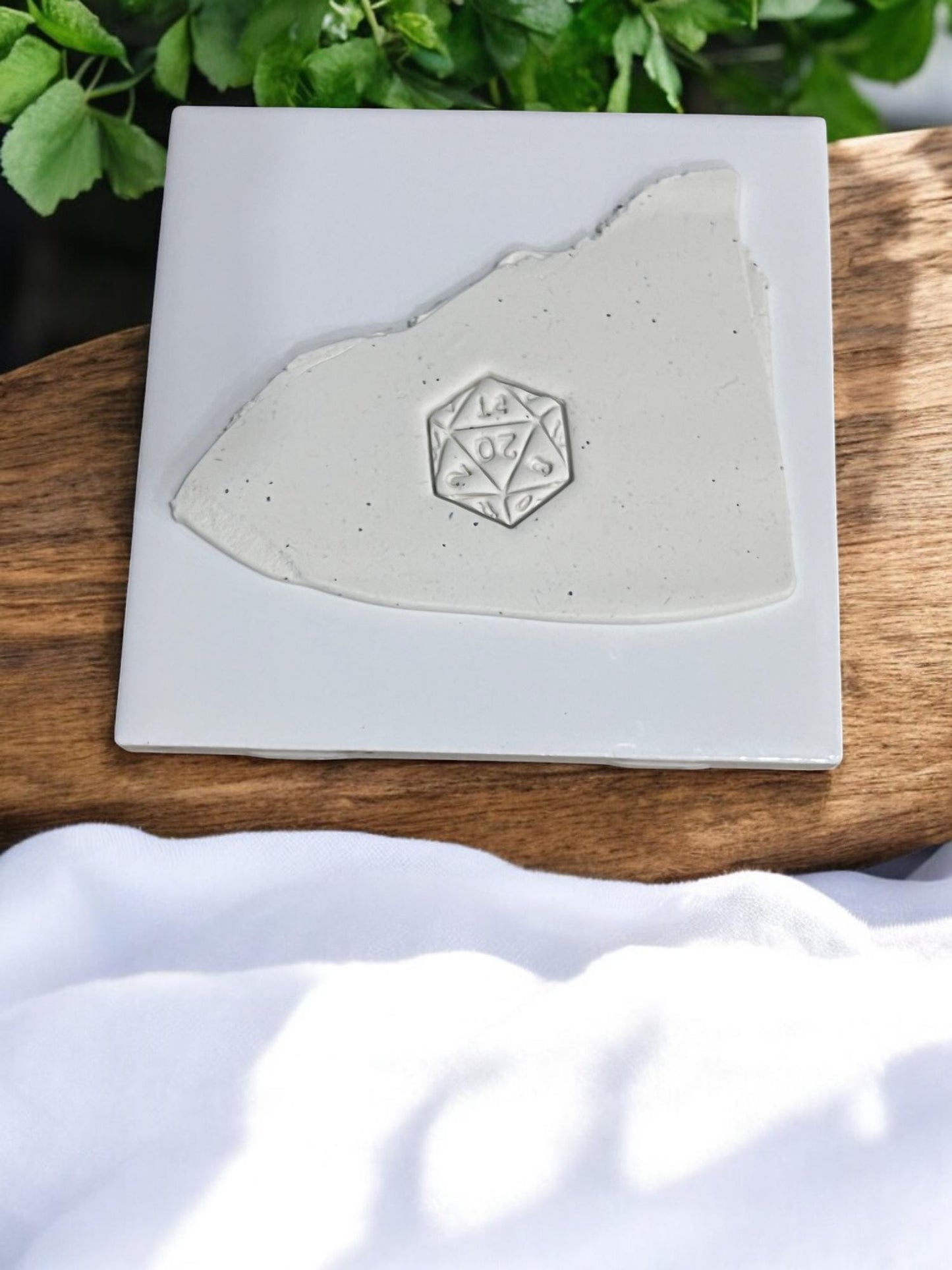 D20 dice design embossed in polymer clay slab on white ceramic tile