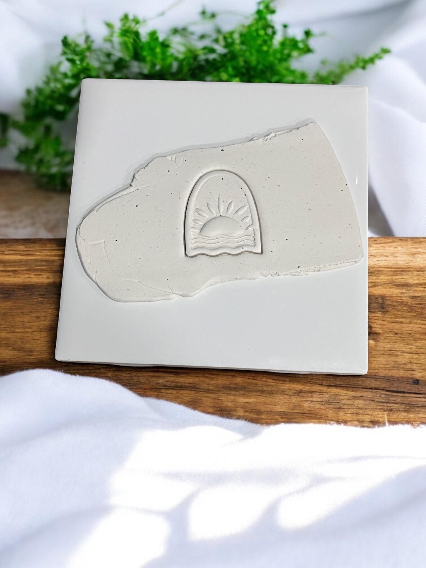 Embossed sunrise design pressed into clay slab on ceramic tile