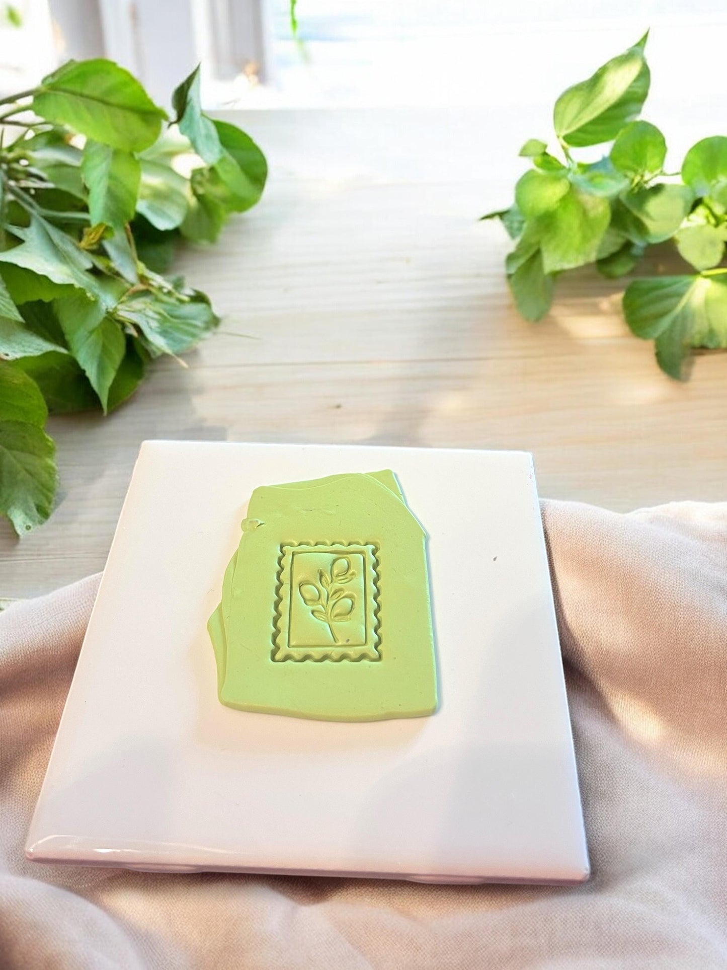 Green lemon stamp impression on clay slab, showcasing a playful citrus leaf design ideal for summer jewelry making.