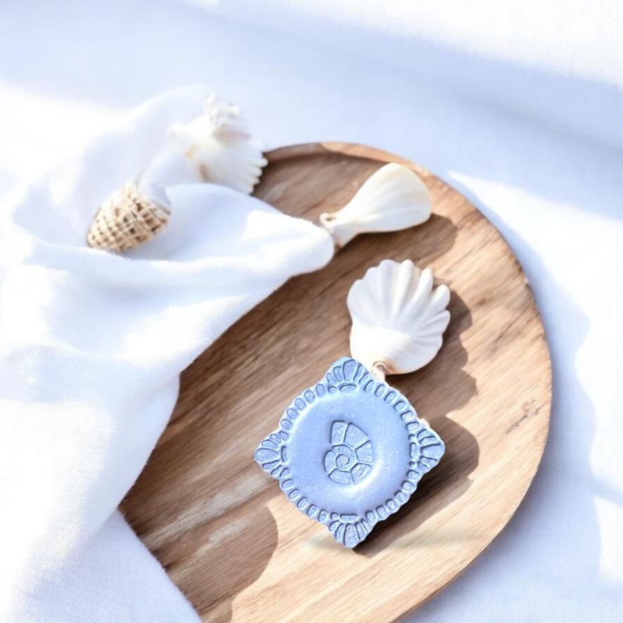 Finished polymer clay seashell piece on wood with seashell props, perfect for boho coastal earring inspiration
