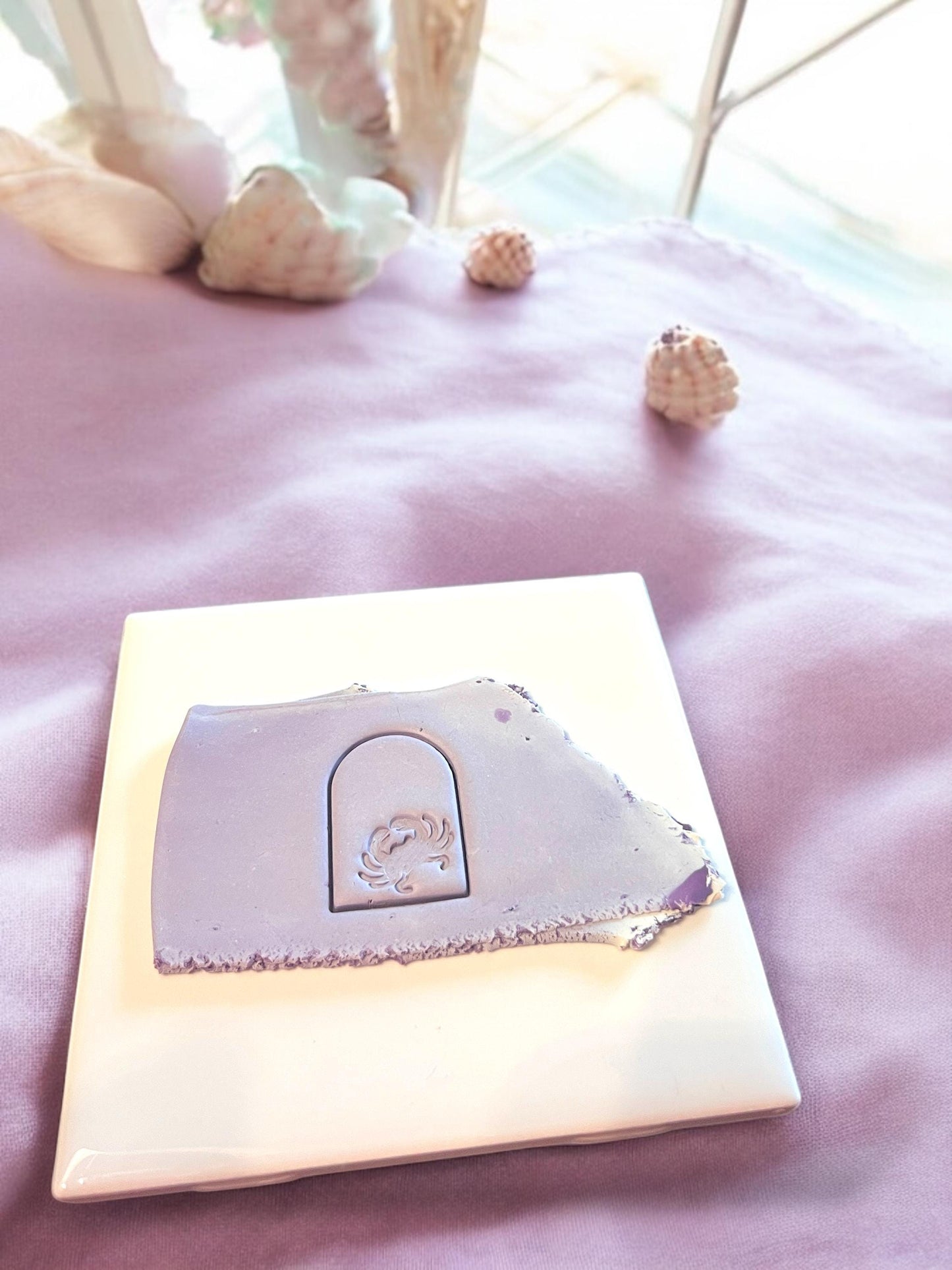 A purple slab of polymer clay featuring a crab arch impression, perfect for coastal-themed clay projects.