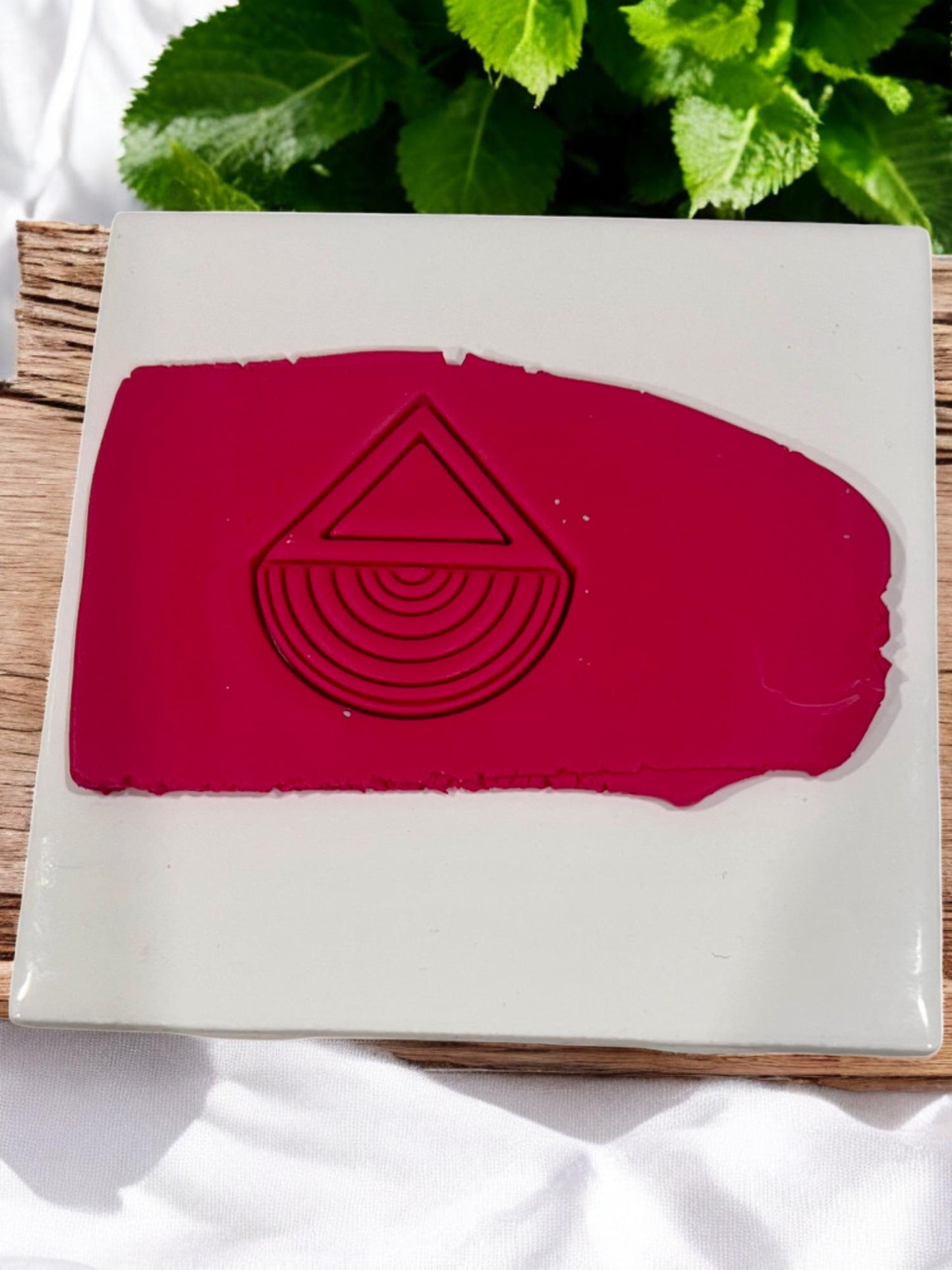 Pressed geometric design in deep red clay on ceramic tile