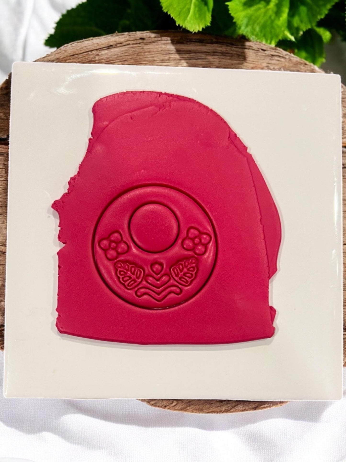 Red polymer clay slab with impression of floral folk hoop earring design, showing detailed flowers and leaves