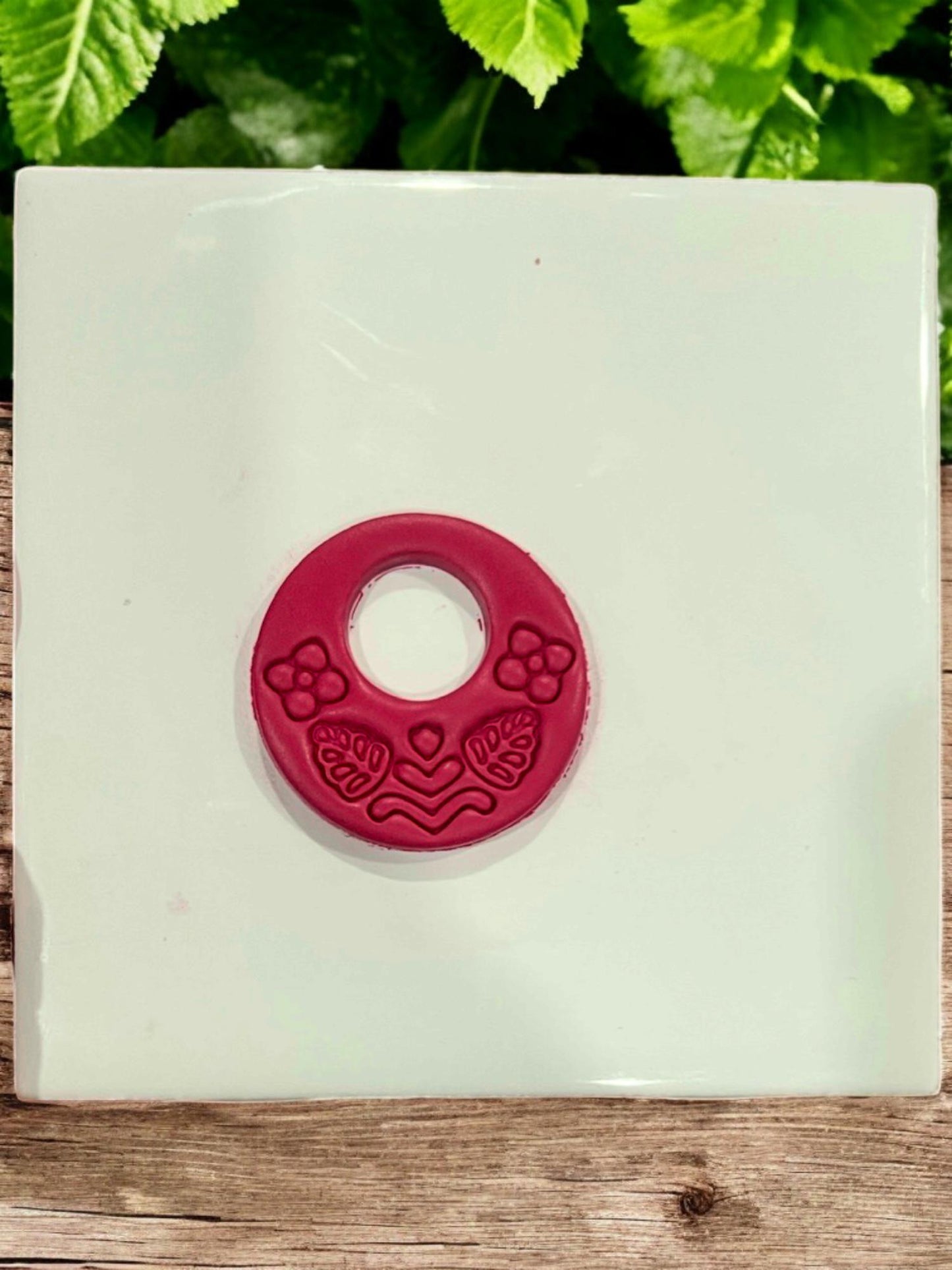 Cut polymer clay hoop earring with symmetrical floral and leaf details from folk-inspired cutter