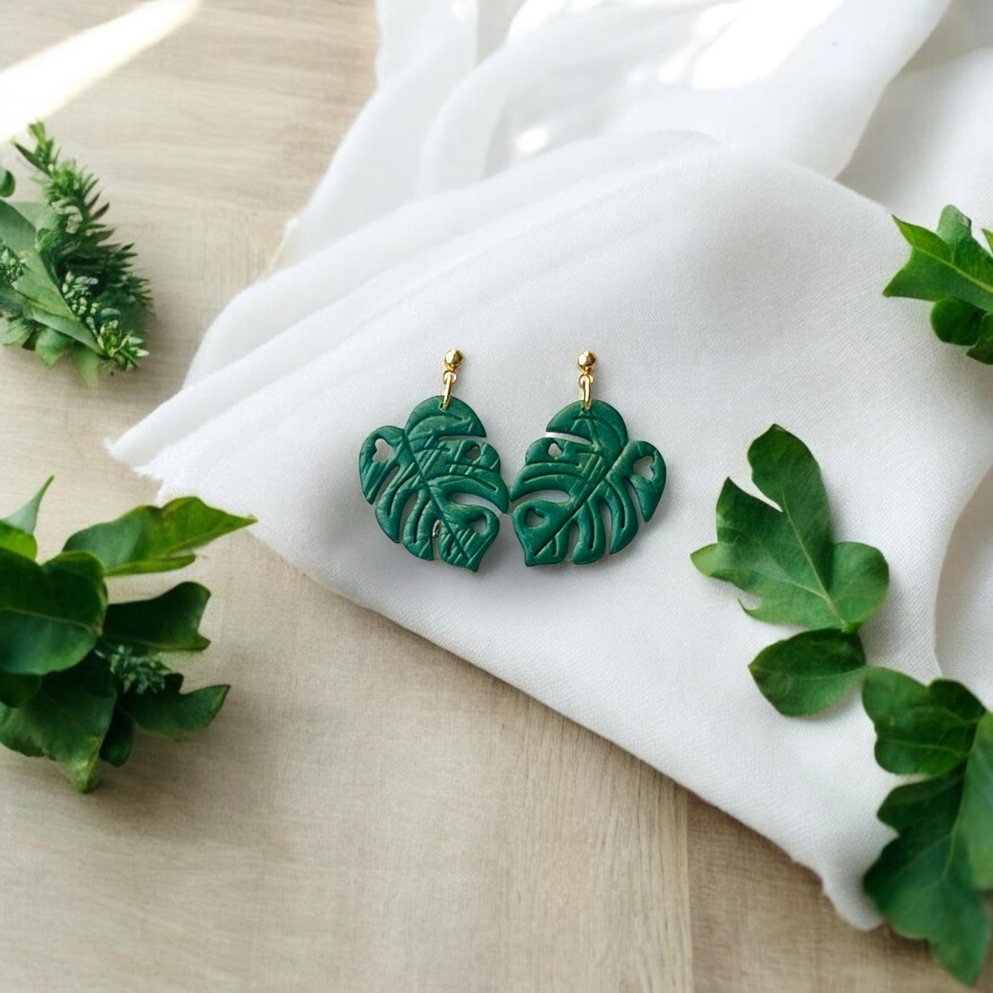 finished green earrings on fabric with leaves
