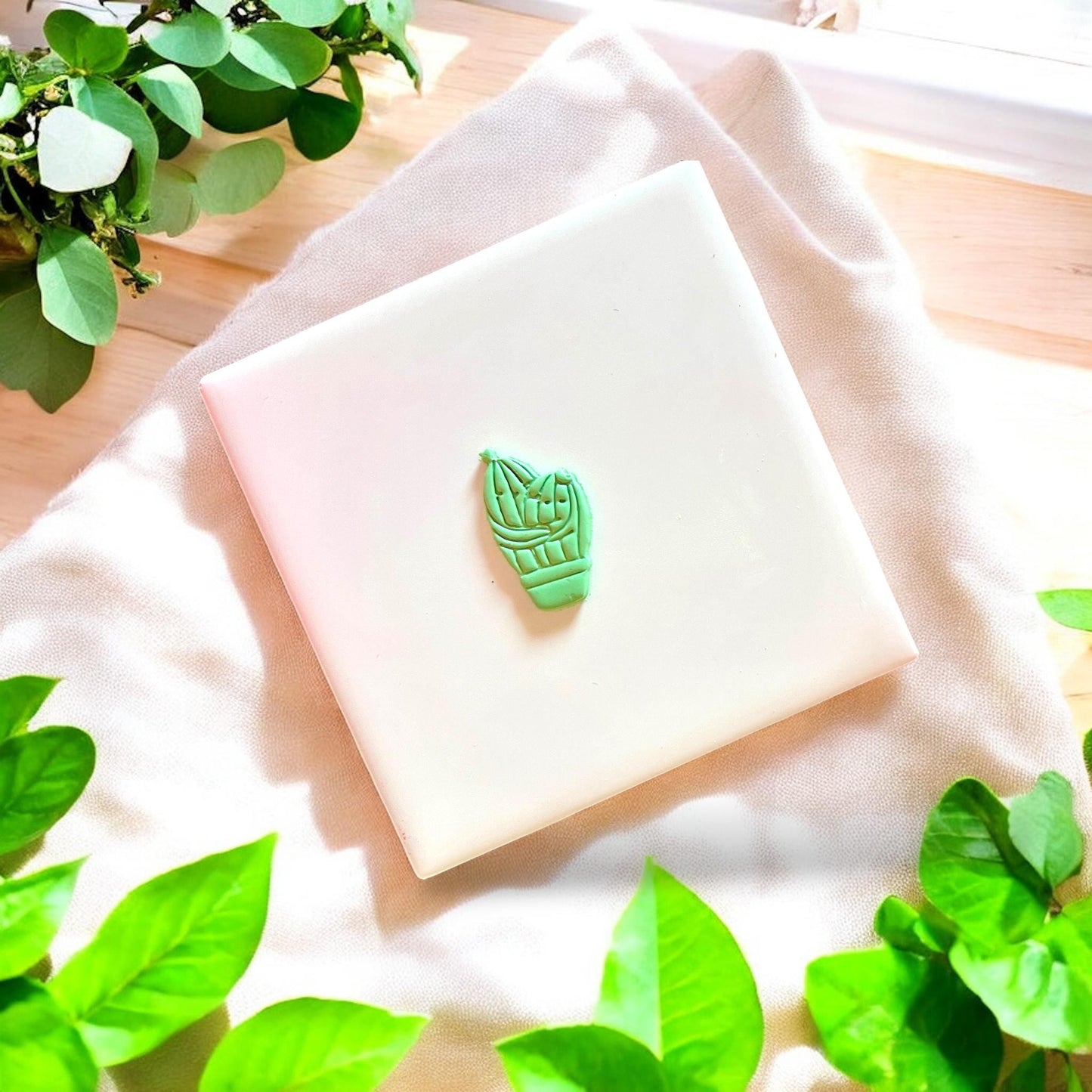 Finished cactus shape cut from green clay sitting centered on a white tile
