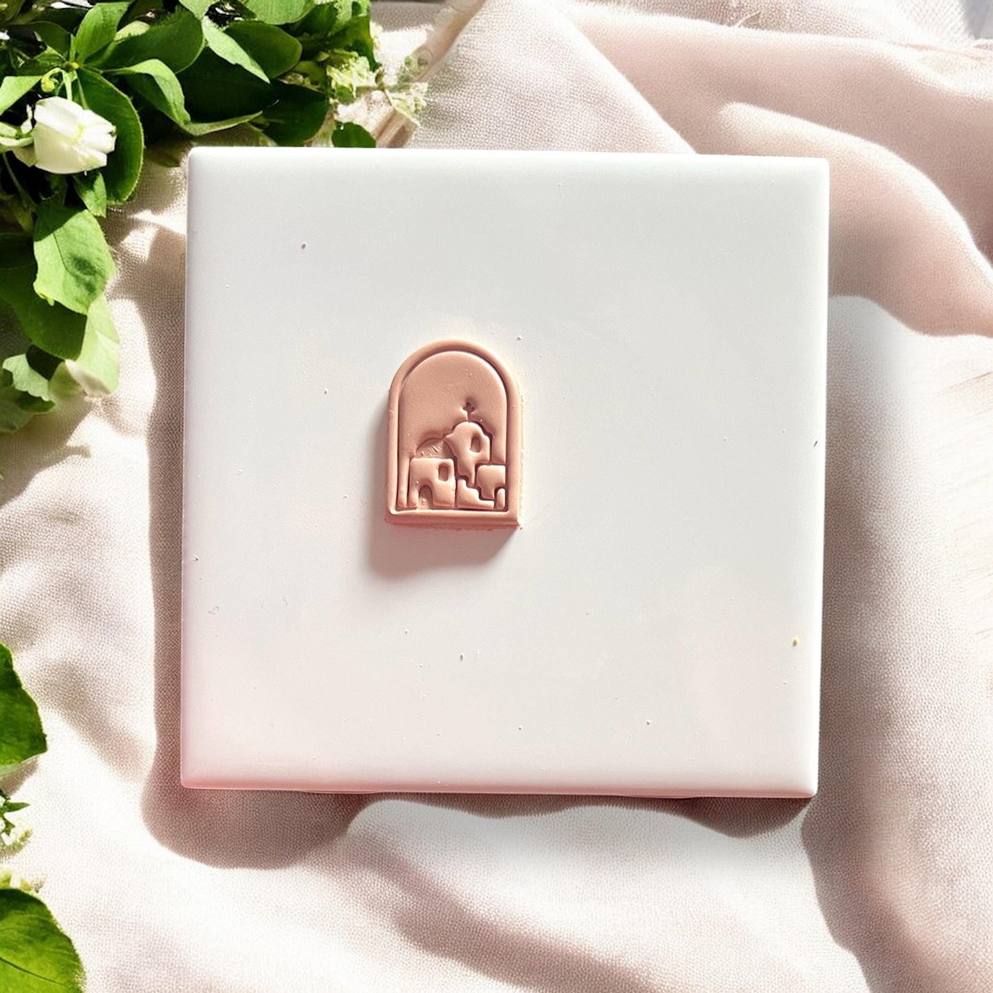 Cleanly cut Santorini village design in terracotta clay, centered on a white tile.