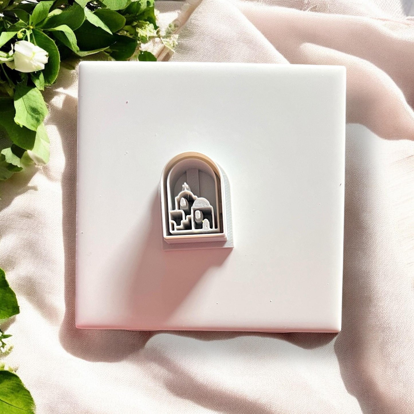White plastic arch cutter resting in the matching Santorini clay piece, showing alignment.