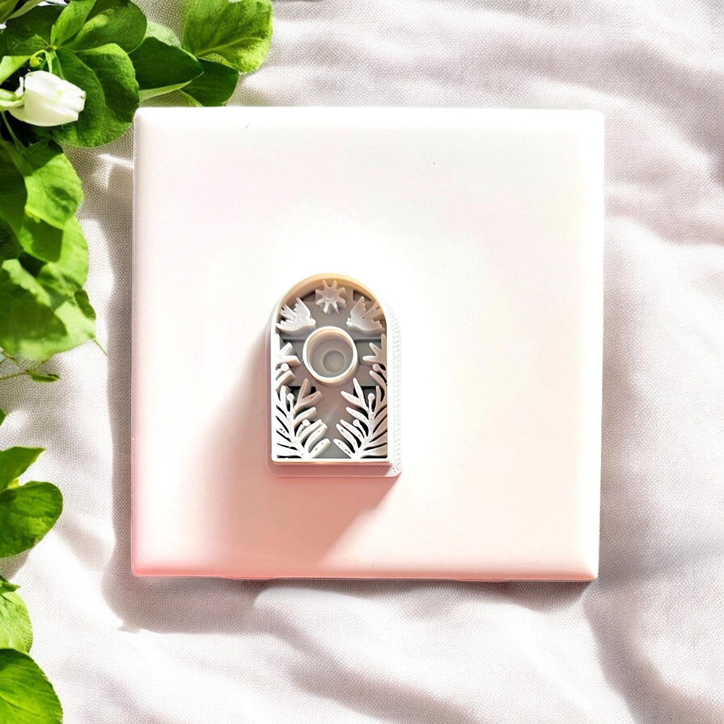 White plastic cutter placed over the green arch earring piece for sizing view