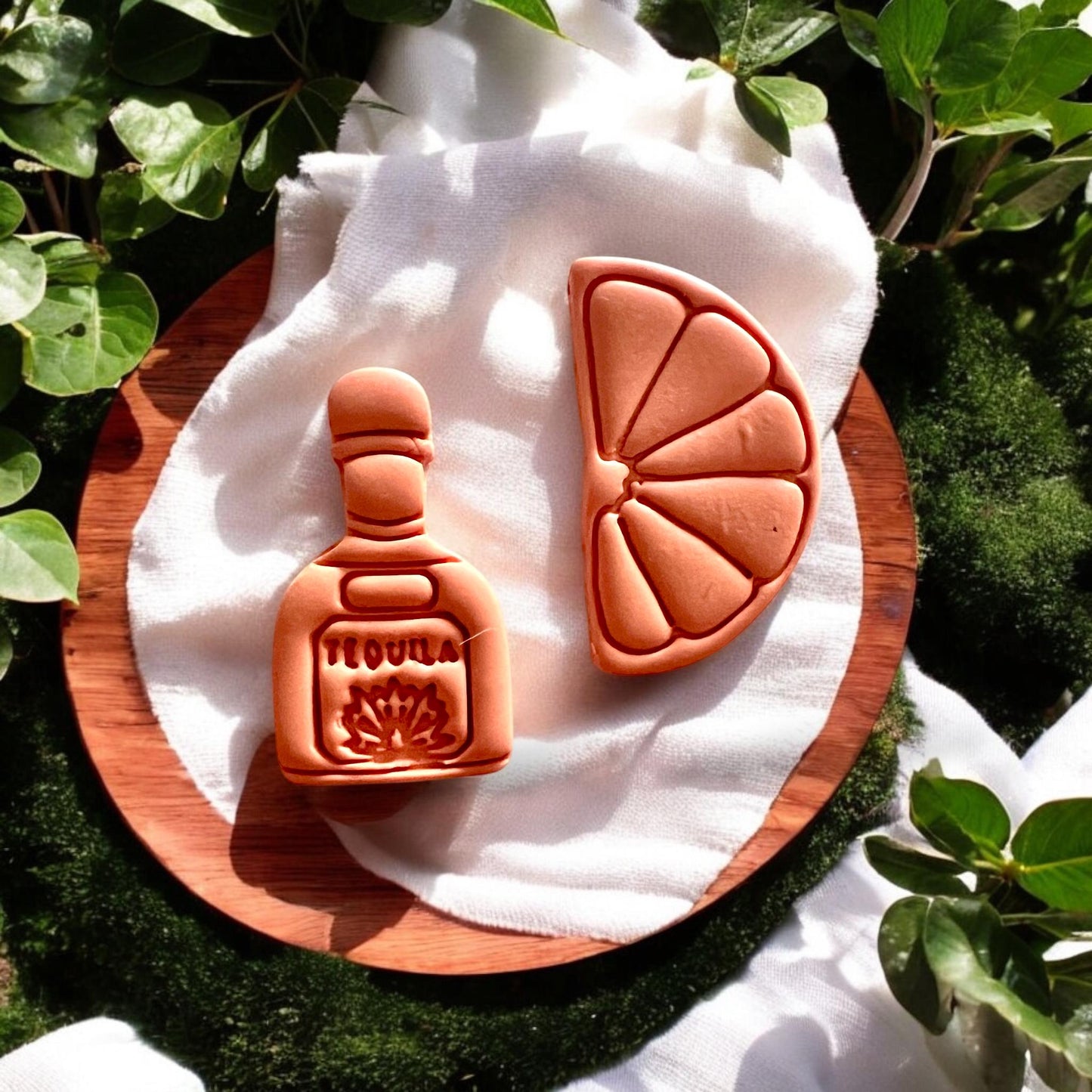 Styled tequila and lime clay earrings on wooden tray with greenery