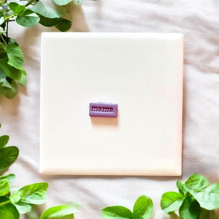 Small purple "mama" clay charm fully cut and placed on display tile
