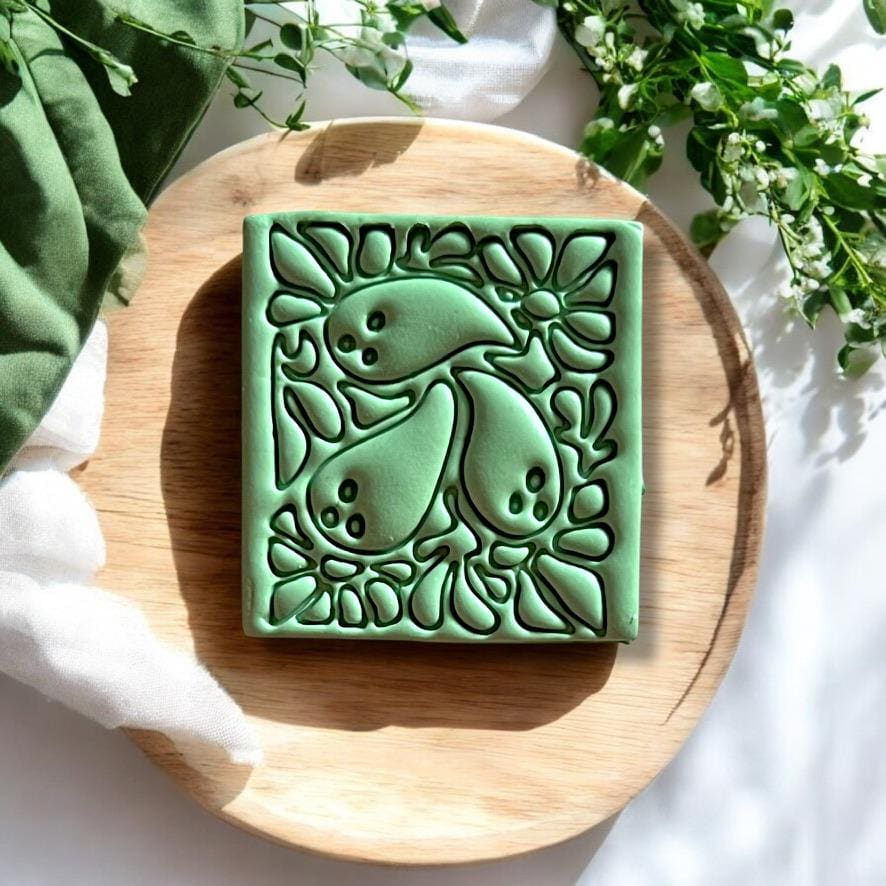 Finished ghost Matisse green polymer clay earring design shown on a wooden surface.