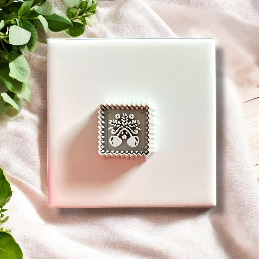Cherry stamp polymer clay cutter positioned on tile before pressing, showcasing scalloped square cutter shape