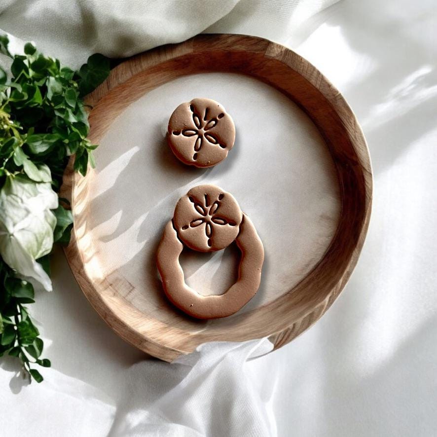 Display of assembled sand dollar dangle earrings made using the polymer clay cutter set, styled for summer creativity.
