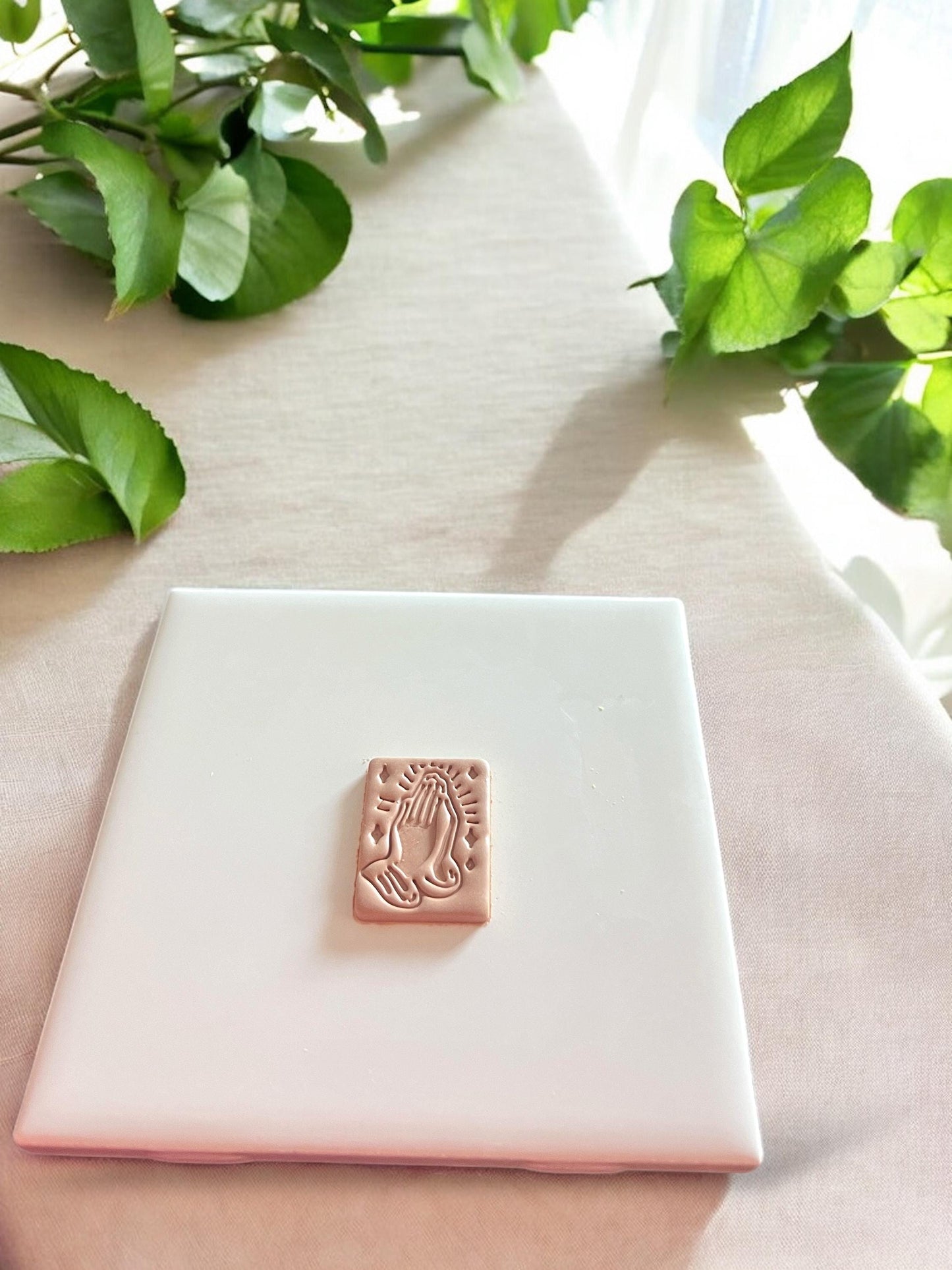 A completed clay piece featuring a raised praying hands design, ideal for religious or faith-based clay earrings